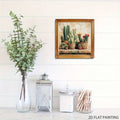 Framed cactus artwork hung over a white paneled wall beside a lantern and glass jar