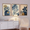 Navy botanical three-panel wall art displayed above a white sideboard with a warm table lamp