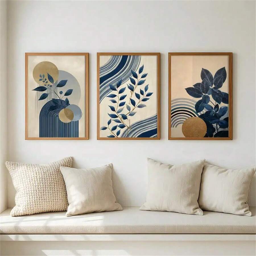 Framed navy leaf artwork arranged above a neutral bench with cream pillows in a bright room