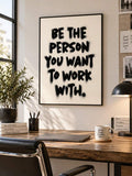Motivational typography poster above a wooden home office desk with plants