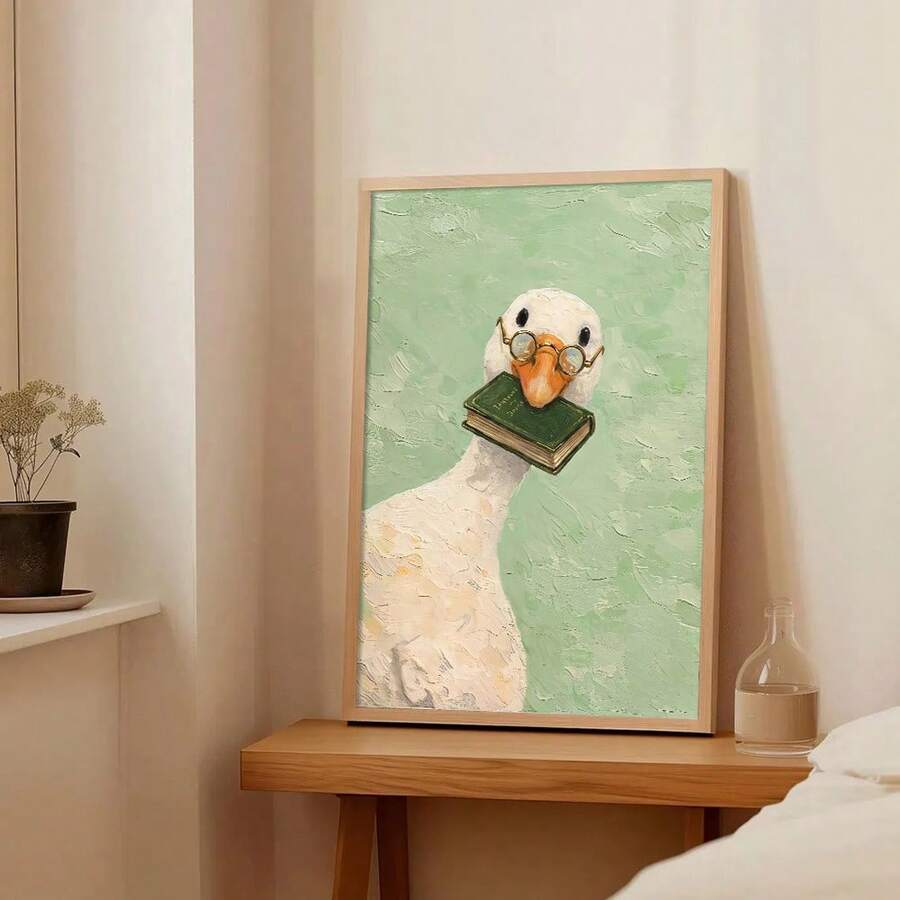 Framed bookish goose artwork resting on a light wood console