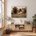 Framed countryside cottage canvas displayed in a bright neutral living room