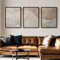 Three-panel neutral wall art displayed above a brown leather sofa