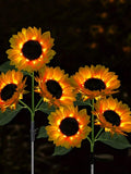 Glowing solar sunflower stake lights with warm LEDs in dark garden