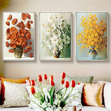 Three framed vase flower prints above a bright living room sofa