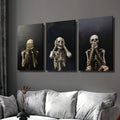 Three gothic skeleton prints in expressive poses arranged above a light sofa