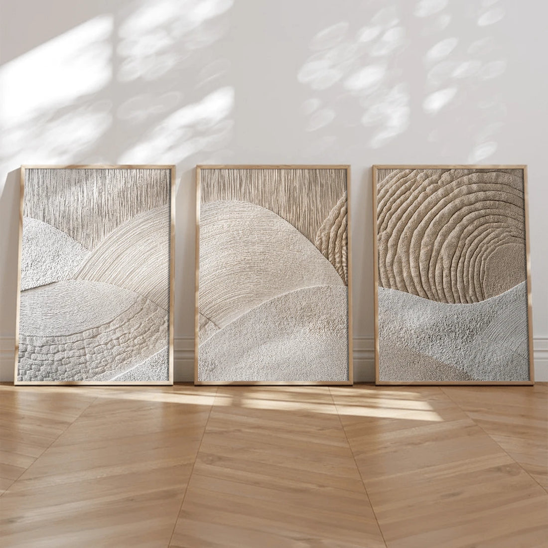 Three framed neutral textured abstract canvas panels with sweeping ivory relief shapes