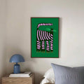 Framed green wall art with black cat and pink stripes above bedside table
