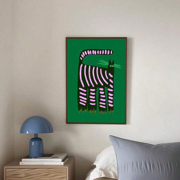 Framed green wall art with black cat and pink stripes above bedside table