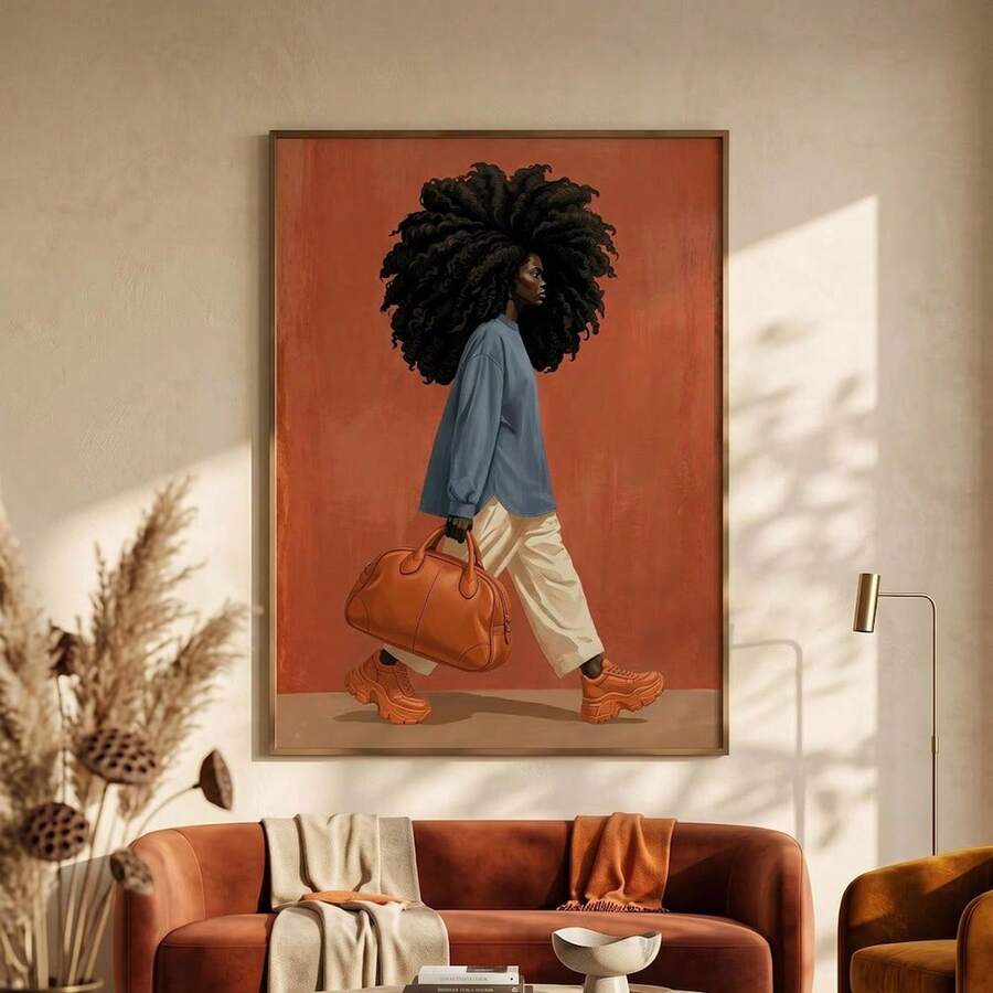 Framed fashion artwork of a Black woman with curls, blue shirt, and orange handbag above a brown sofa