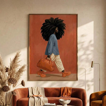 Framed fashion artwork of a Black woman with curls, blue shirt, and orange handbag above a brown sofa