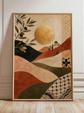 Framed olive branch canvas poster with ochre sun, terracotta hills and geometric motifs leaning against a paneled wall