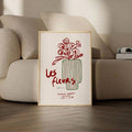 Framed Les fleurs vase print leaning beside a beige living room sofa