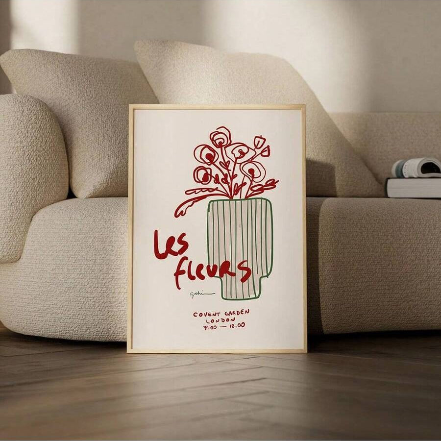 Framed Les fleurs vase print leaning beside a beige living room sofa