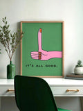 Framed pink thumbs-up print reading It's All Good above a home office desk