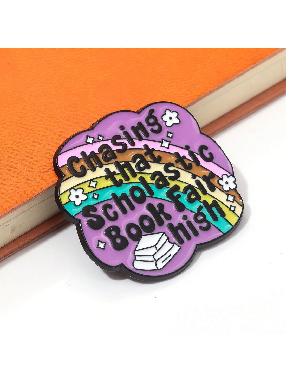 Upgrade your style with our Chasing Scholastic Dreams book fair brooch pins. Made with vibrant enamel, these pins are perfect for showcasing your love for literature. Add a touch of fashion to your outfit while inspiring others to chase their dreams.
