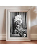 Silver framed black and white cheetah wearing a towel turban on a wood floor