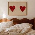 Red heart couple artwork in a wood frame above a bed
