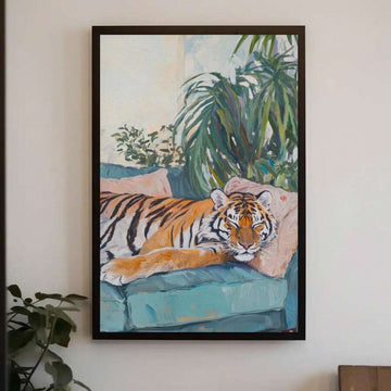 Black framed tiger painting on a white wall with teal sofa and tropical plants
