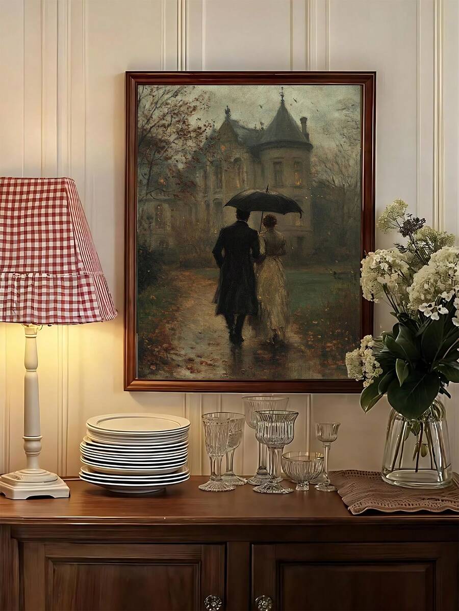 Framed romantic painting of couple walking under umbrella beside manor, styled above buffet with lamp and flowers