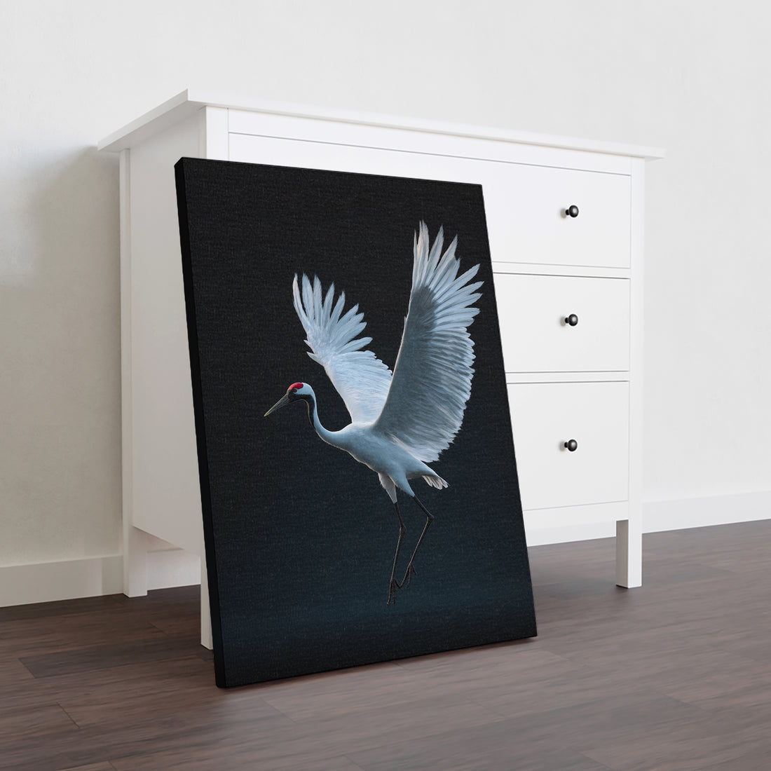 This striking canvas print captures an elegant white crane in dramatic contrast against a deep black background, creating a sophisticated focal point for any interior space. The minimalist composition draws the eye with its refined simplicity, making it ideal for modern and contemporary settings.