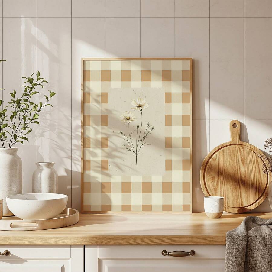 Framed daisy botanical print with a cream and tan gingham border on a sunlit kitchen counter