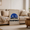 Framed ARE YOU POOPING funny blue face print leaning against cream sofa in neutral living room