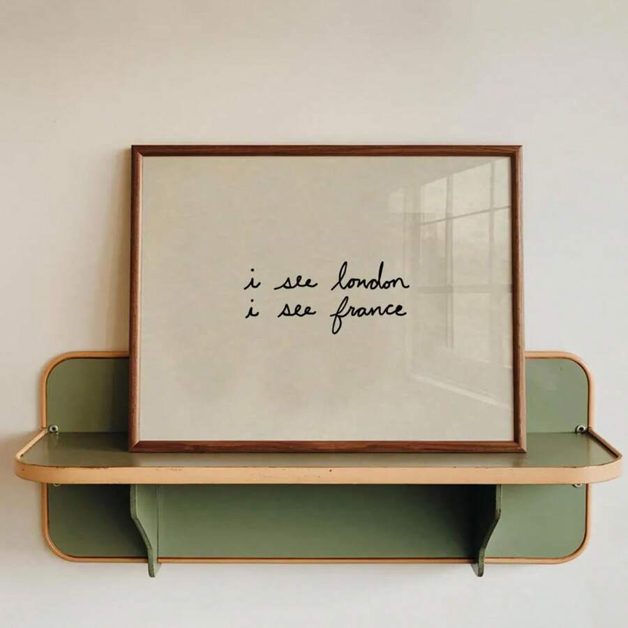 Framed ivory canvas with handwritten I see London I see France travel quote on a green shelf