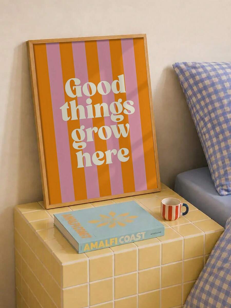 Framed orange and pink Good things grow here art on a yellow tiled bedside table