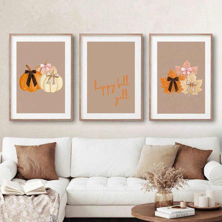 Three framed fall prints with pumpkins, happy fall y’all quote, and bow-tied leaves above a white sofa