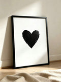 Textured black heart on white canvas shown in a slim black frame leaning against a wall. Heart Shaped Graffiti Abstract Black & White Canvas Poster