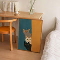 Three stacked cats in teal and mustard wall art beside a modern bedroom desk