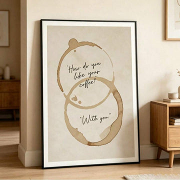 Framed coffee quote poster with brown mug-ring stains leaning beside a wood cabinet in neutral home decor