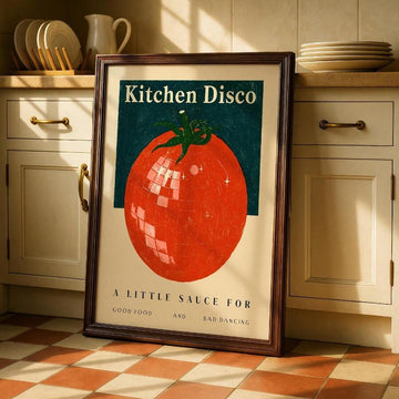 Framed Kitchen Disco tomato disco-ball poster in a sunlit vintage kitchen with cream cabinets