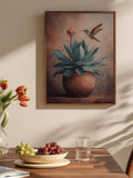 Framed hummingbird hovering over blue-green agave in a terracotta planter