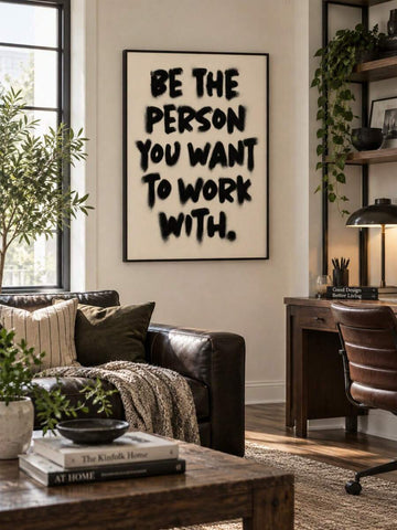 Framed cream canvas with bold black brush lettering above a leather sofa