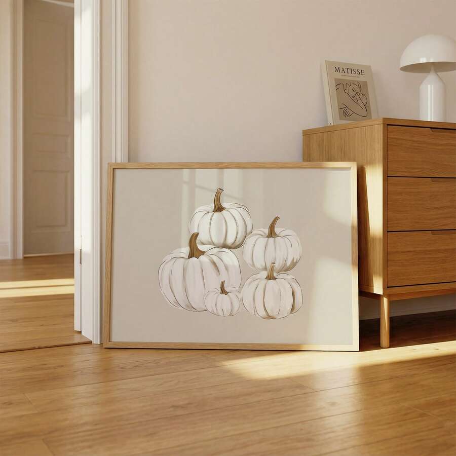Framed white pumpkin canvas print leaning beside a wood dresser in a sunlit bedroom