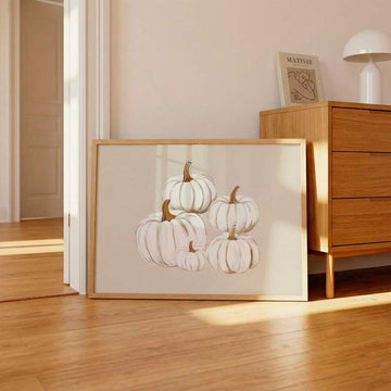 Framed white pumpkin canvas print leaning beside a wood dresser in a sunlit bedroom