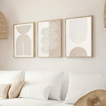 Three framed beige geometric prints with arches and line art above a white bed in a neutral bedroom