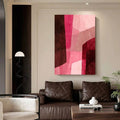 Abstract pink and burgundy geometric canvas art displayed above a cognac leather sofa