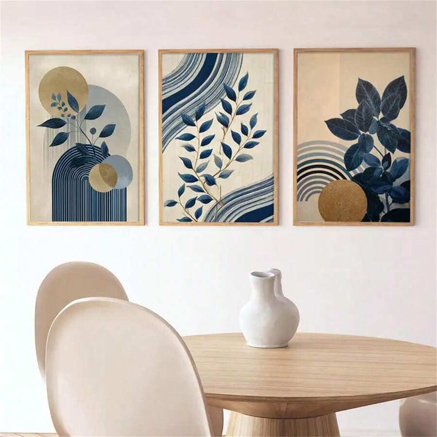 Three framed navy botanical prints with geometric gold and blue accents above a light wood dining table