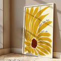 White-framed mustard sunflower quote print leaning against a sunlit beige wall