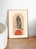 Framed fern canvas print with terracotta shapes beside a white chair