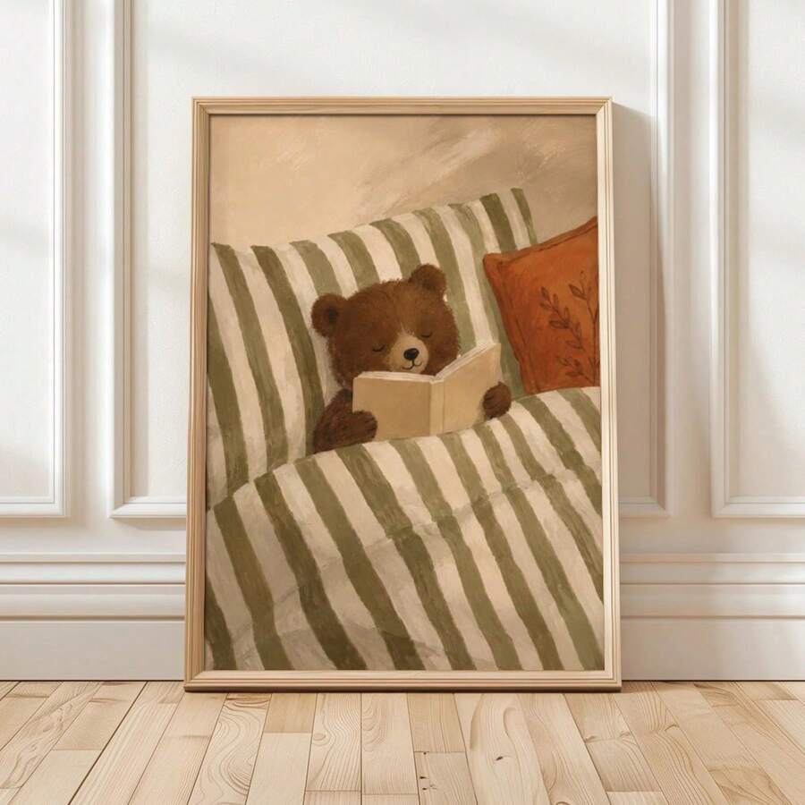 Framed nursery print of a brown bear reading beneath a sage striped blanket