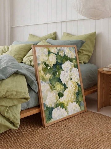 Framed white hydrangea watercolor canvas leaning beside sage and blue bedroom pillows
