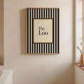 Framed The Loo typography print with black vertical stripes on cream bathroom wall