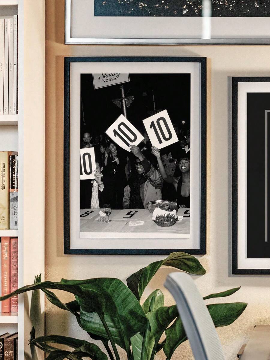 Retro fashion event wall art displayed in a light wood frame above a dining area