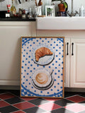 Framed croissant and coffee canvas with a cobalt blue tiled border