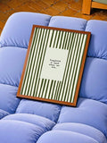 Olive green striped happiness quote canvas poster shown in a brown wood frame on a blue sofa