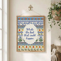 Framed positive quote embroidery poster hanging beside flowering plant